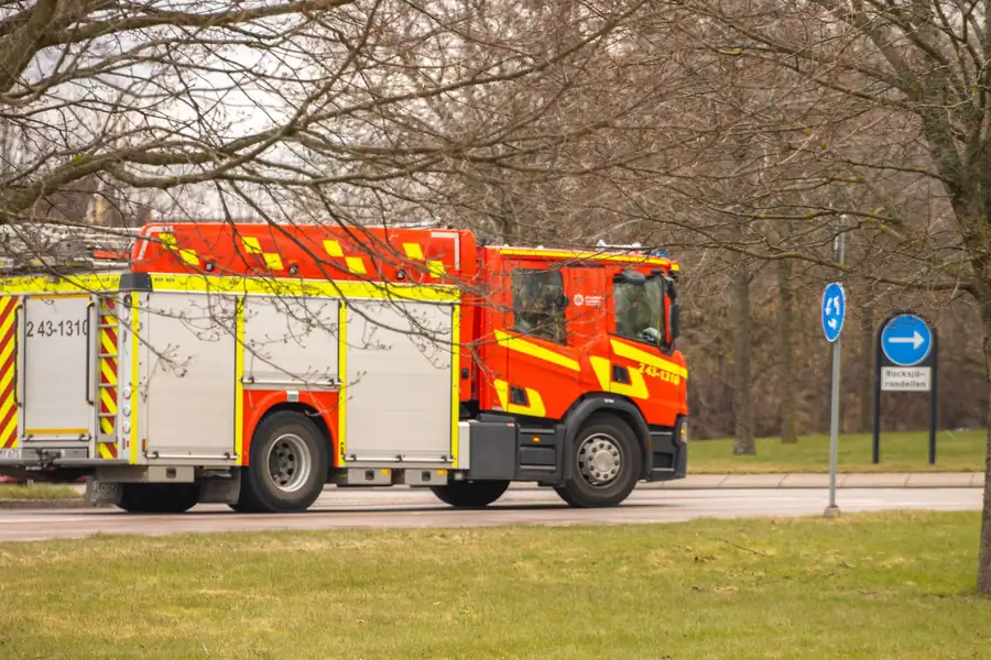 Red fire engine with high-visibility chevrons parked by a tree-lined road, reflecting fire service input on battery storage plans