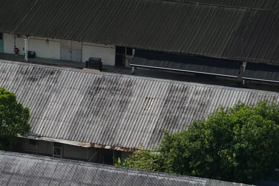 Rows of older industrial shed roofs with weathered grey corrugated sheeting, the type that needs a structural check before solar