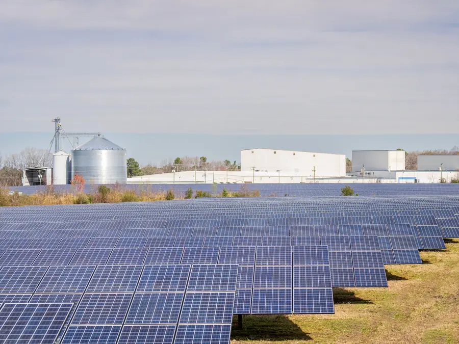Ground-mounted solar array in front of grain silos and farm buildings