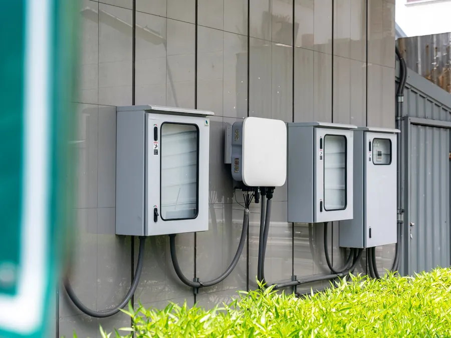 Wall-mounted inverter and battery control units with isolators fixed to the outside wall of a commercial building